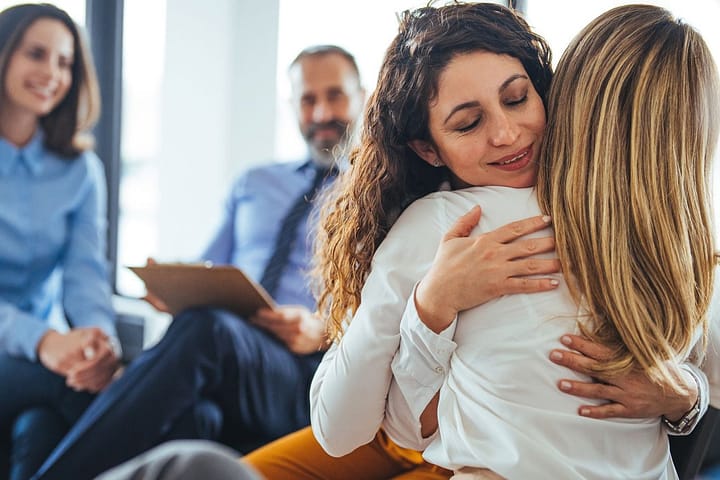 Woman overcomes addiction through therapy. Her therapist gives her a hug.